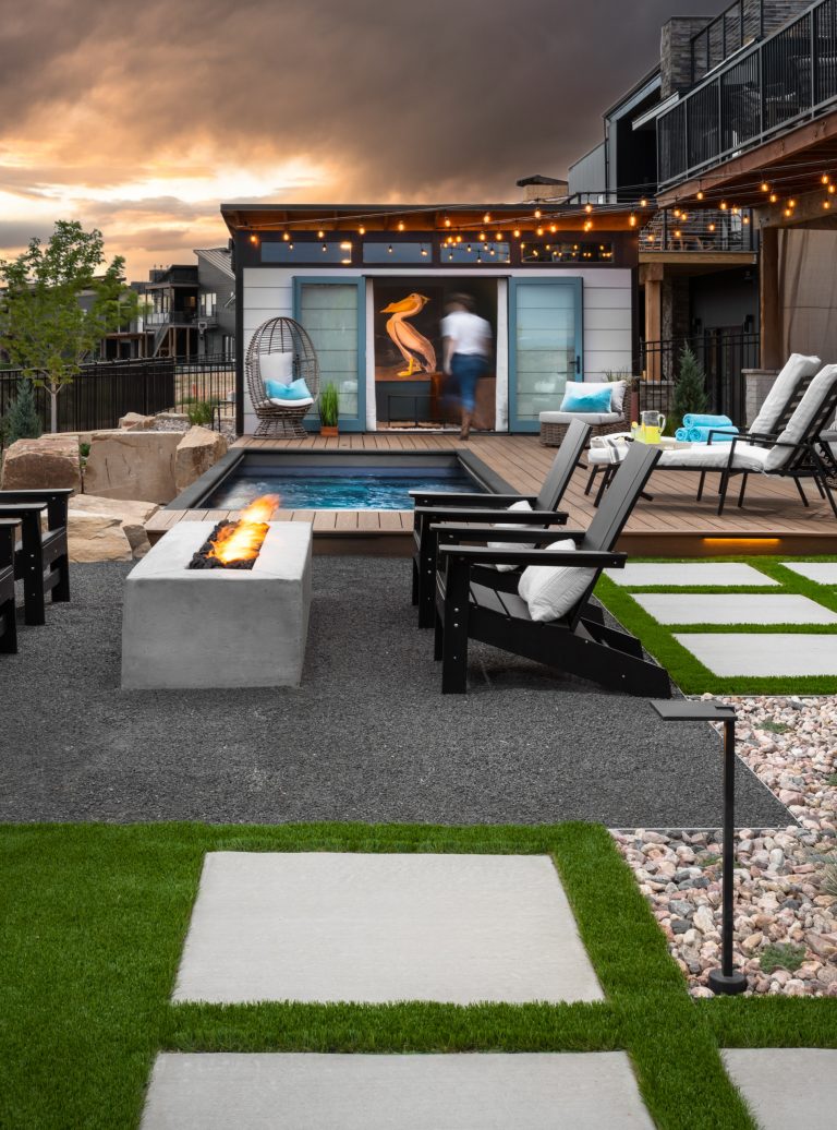 This modern landscape includes a shipping container pool, natural Thermory wood decking, charcoal breeze patio @ a custom concrete fire pit. Slab steppers cut into synthetic turf add circulation and a graphic punch while staying low maintenance. Being perched on a hilltop, the pool shell and boulder walls retain the upper living spaces, and help transition to the rear elevation of the lot, and native open space beyond the fence.