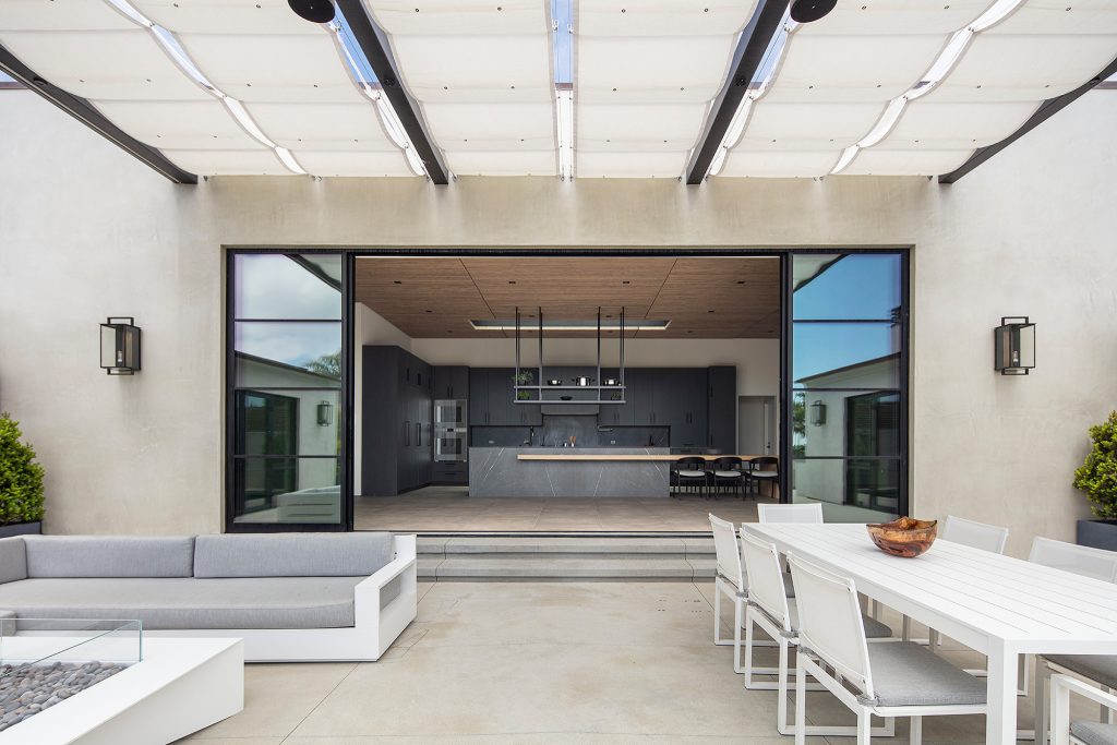 Huge trendy courtyard concrete patio photo in Los Angeles with a fire pit and an awning