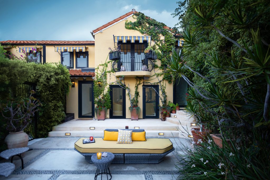 Patio - large modern front yard concrete patio idea in Los Angeles with a fire pit and an awning