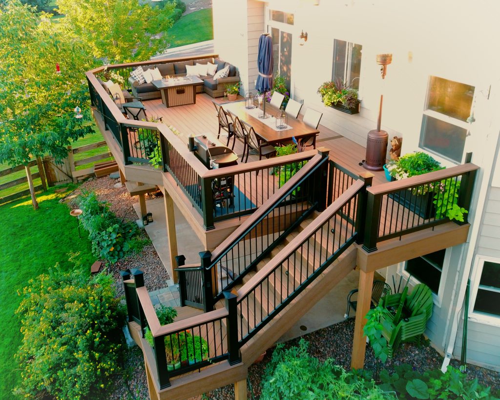 Second story upgraded Timbertech Pro Reserve composite deck in Antique Leather color with picture frame boarder in Dark Roast. Timbertech Evolutions railing in black was used with upgraded 7.5" cocktail rail in Azek English Walnut. Also featured is the "pub table" below the deck to set drinks on while playing yard games or gathering around and admiring the views. This couple wanted a deck where they could entertain, dine, relax, and enjoy the beautiful Colorado weather, and that is what Archadeck of Denver designed and built for them! by Archadeck of the Foothills | Fire Pits|Backyard Design|Outdoor Living Spaces|Landscape Design|Backyard Ideas|Landscaping|Landscaping Ideas|Landscape Installation|Fire Feautures|Fire Pit