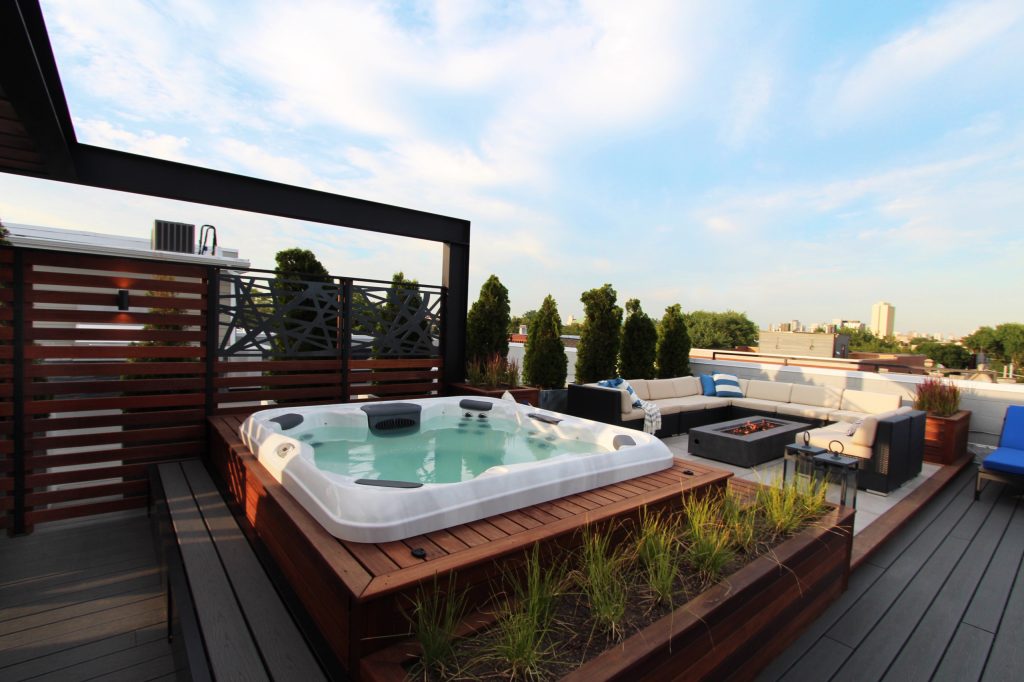 A Built-in Hot tub surrounded by a built in Ipe deck and bench with a built-in planter box. The lounge area has a large fire-pit as the focal piece.