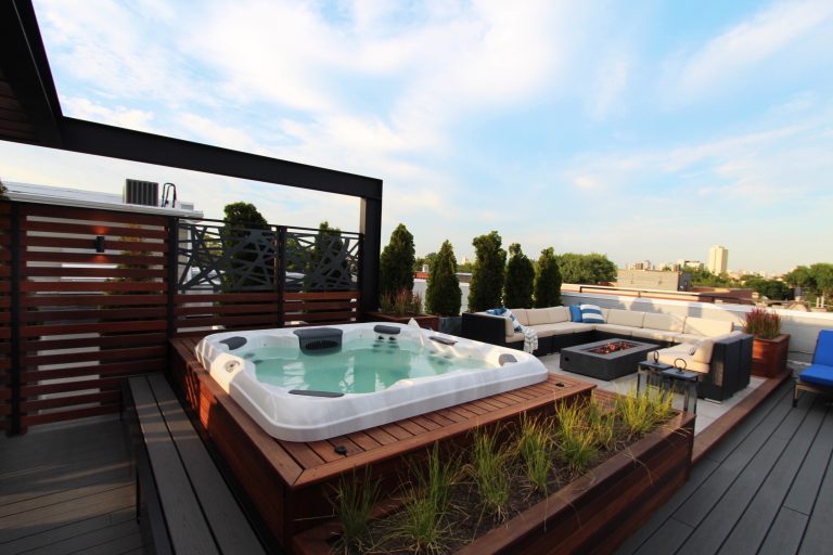 A Built-in Hot tub surrounded by a built in Ipe deck and bench with a built-in planter box. The lounge area has a large fire-pit as the focal piece.