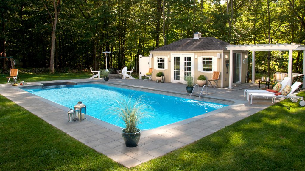 A beautiful backyard with a pool house, pergola, outdoor shower and a fire pit. Perfect for entertaining on a warm summer afternoon.