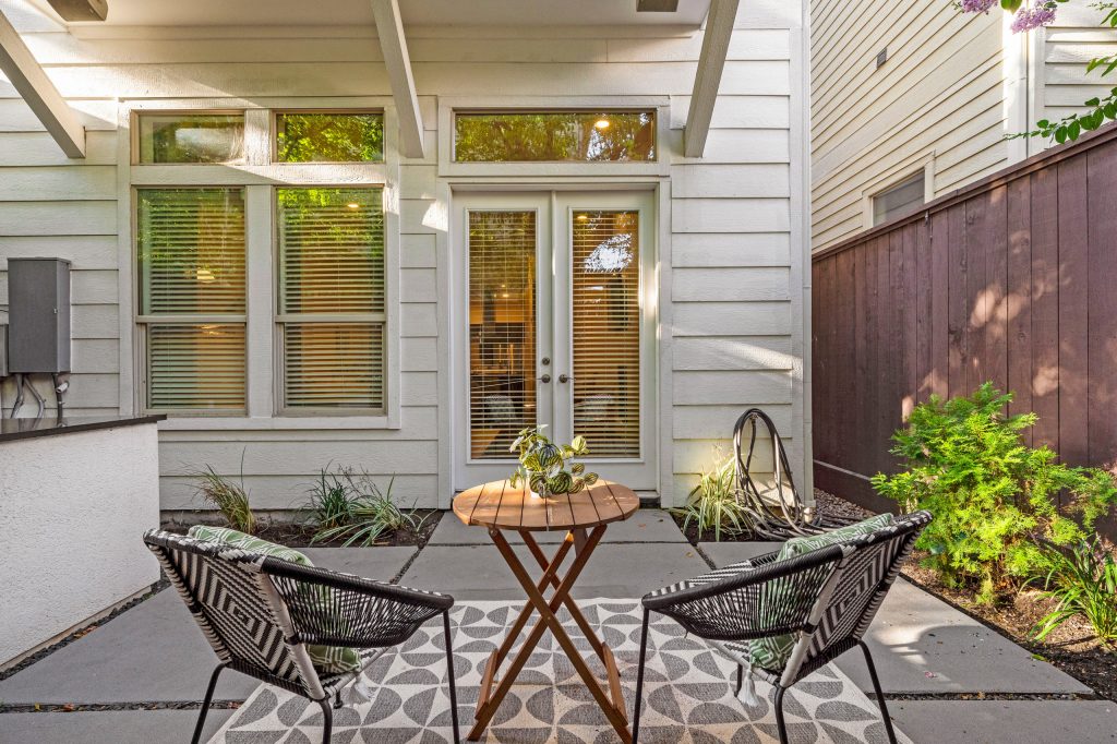 A cozy cafe seating area on the back patio area offers an eclectic/modern pop to flow with the interior furnishings while adding some fun color and pattern.