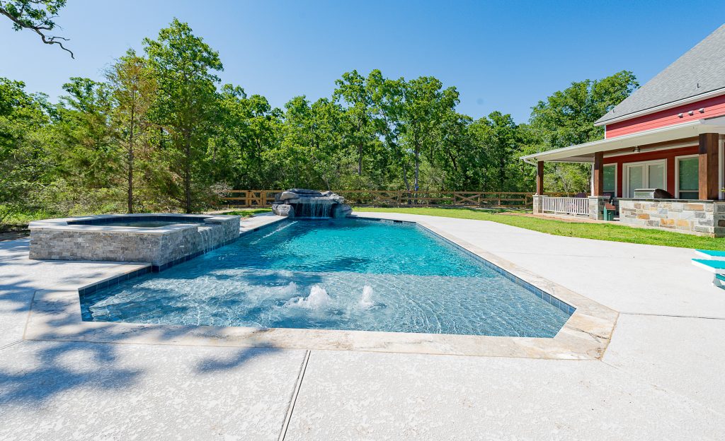 A geometric pool with a spa and a grotto water feature. Travertine is the coping and Pebble Tech is the finish in the pool. Hot tub - large modern backyard concrete and custom-shaped hot tub idea in Other by Todd Homes | Pool design | Pool Contracting | Swimming Pool Ideas | Swimming Pool Design Ideas