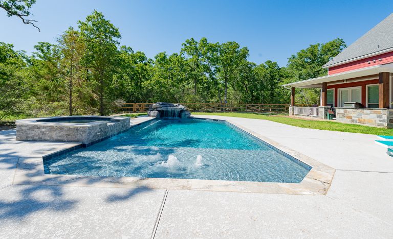 A geometric pool with a spa and a grotto water feature. Travertine is the coping and Pebble Tech is the finish in the pool. Hot tub - large modern backyard concrete and custom-shaped hot tub idea in Other by Todd Homes | Pool design | Pool Contracting | Swimming Pool Ideas | Swimming Pool Design Ideas