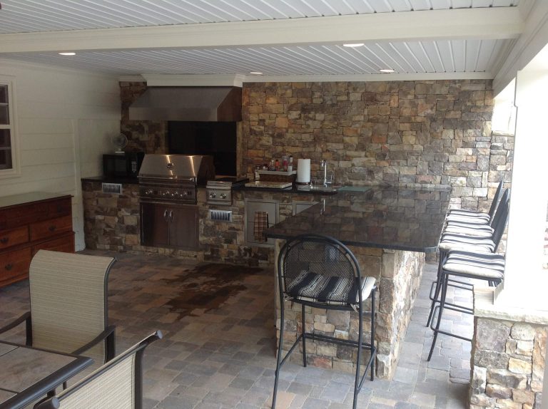 A great example of an outdoor kitchen under cover. We used paver stones with natural stacked stone walls to complete the look. We also built the deck and patio here as well!