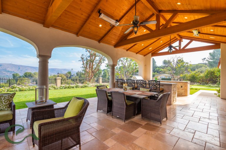 A large covered patio feature multiple seating and dining areas with a fire pit and BBQ island. It's view expand out into the surrounding yard that feature a remodeled swimming pool w/ spa and lawn area.