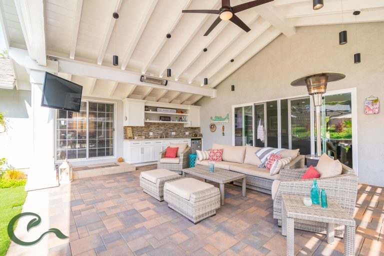 A roof extension off the back of the house creates a large outdoor room for entertaining and relaxing. The space features a bar, TV, heating, and plenty of lighting.