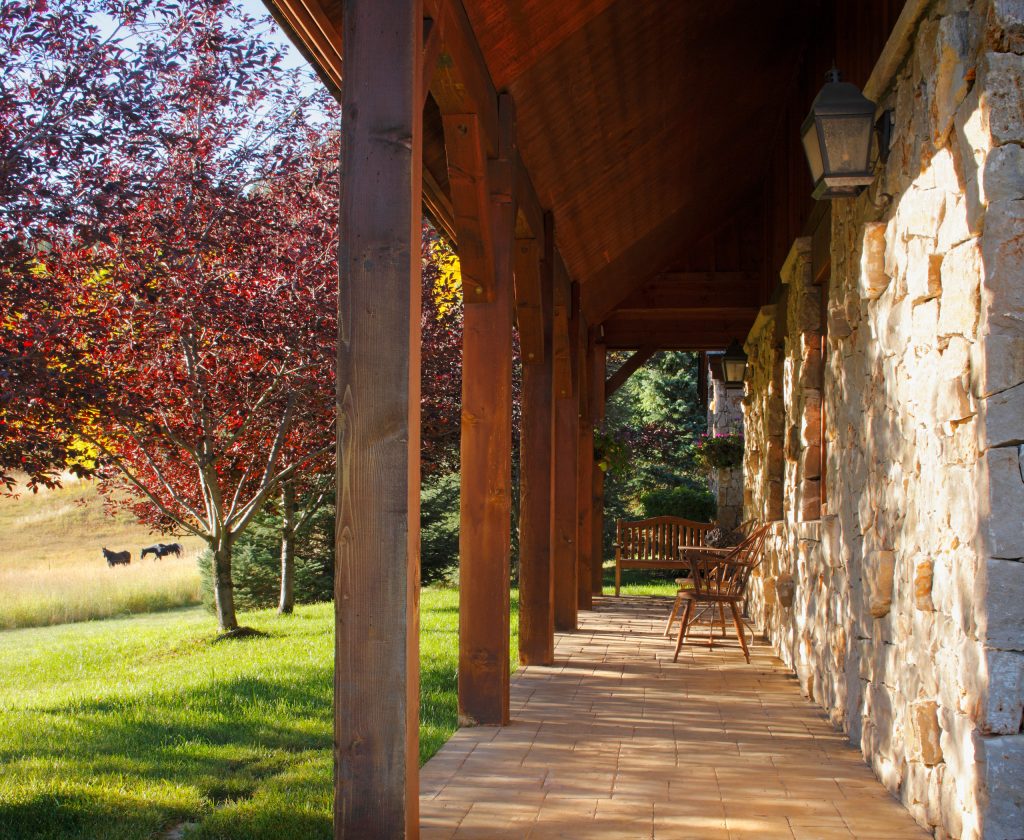 A rustic back porch with wood beams and stone walls set on a hillside outside Vail, Colorado.