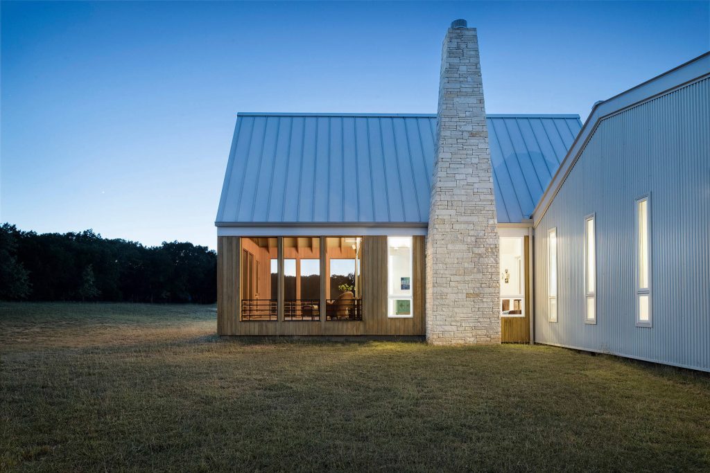 A tapering limestone chimney was inspired by an existing shed on the 47-acre property made of dry-stacked local stone. Photo by Paul Finkel | Piston Design by Miró Rivera Architects | Outdoor Photos | Porch | Landscaping | Landscape Design | Outdoor Living Space | Porch Design Ideas | Outdoor Living Space Ideas | Backyard Design