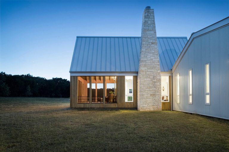 A tapering limestone chimney was inspired by an existing shed on the 47-acre property made of dry-stacked local stone. Photo by Paul Finkel | Piston Design by Miró Rivera Architects | Outdoor Photos | Porch | Landscaping | Landscape Design | Outdoor Living Space | Porch Design Ideas | Outdoor Living Space Ideas | Backyard Design