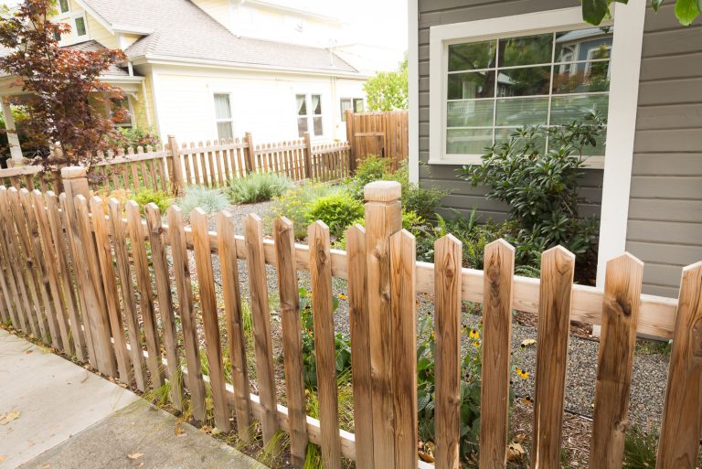 A traditional closed picket cedar fence surrounds a perennial garden (Black-eyed Susan, Sword Fern, Blue Oat Grass, Autumn Moore Grass + Rhododendron) w/ gravel path leading to the backyard. by Regenesis Ecological Design | Outdoor Photos | Porch | Landscaping | Landscape Design | Outdoor Living Space | Porch Design Ideas | Outdoor Living Space Ideas | Backyard Design