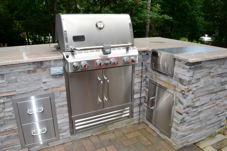 AFTER - Close up of Grill. Outdoor kitchen with Big Green Egg and Weber grill. The bar has a granite top, outdoor sink and cultured stone veneer on the sides. There is plenty of stainless steel storage.