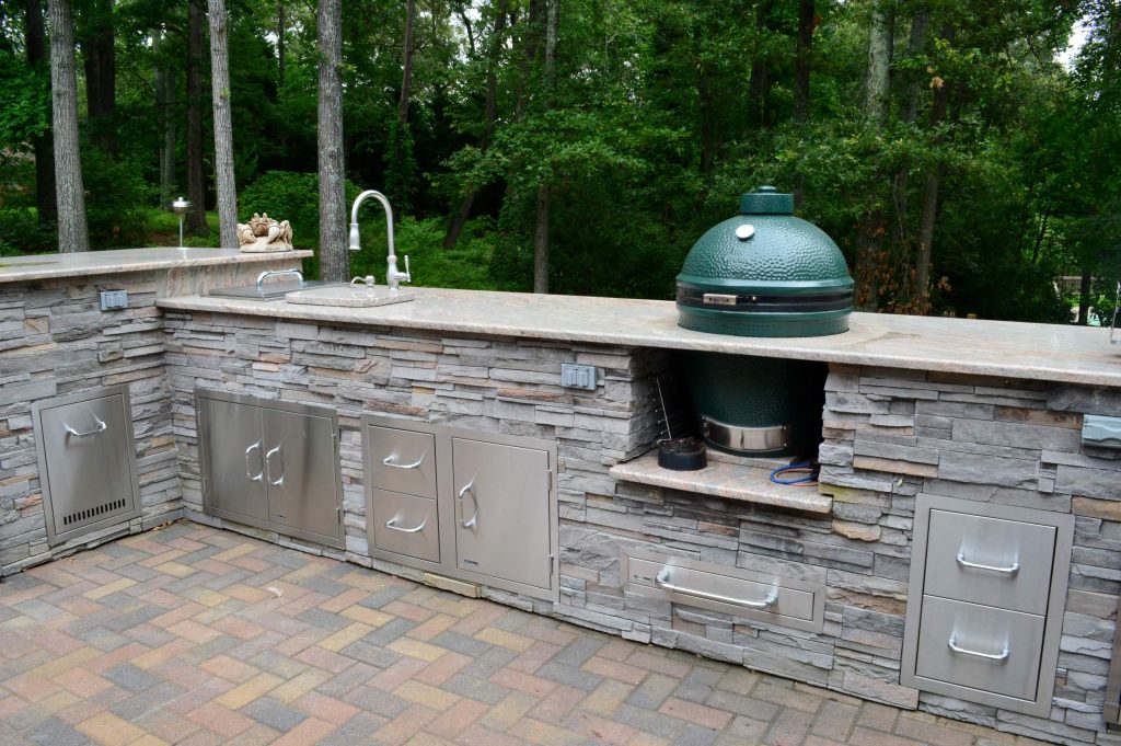 AFTER - Outdoor kitchen with Big Green Egg and Weber grill. The bar has a granite top, outdoor sink and cultured stone veneer on the sides. There is plenty of stainless steel storage.