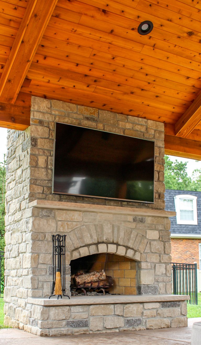 An enchanting outdoor room space with a beautiful fireplace, custom stamped concrete, and an outdoor kitchen.