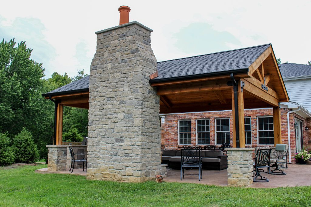An enchanting outdoor room space with a beautiful fireplace, custom stamped concrete, and an outdoor kitchen.