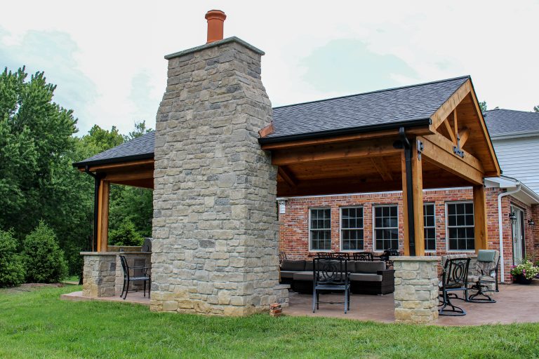 An enchanting outdoor room space with a beautiful fireplace, custom stamped concrete, and an outdoor kitchen.
