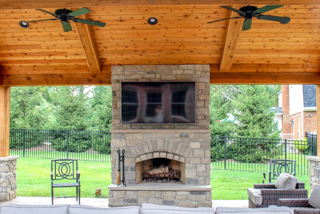 An enchanting outdoor room space with a beautiful fireplace, custom stamped concrete, and an outdoor kitchen.