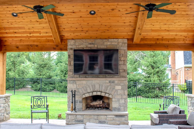An enchanting outdoor room space with a beautiful fireplace, custom stamped concrete, and an outdoor kitchen.