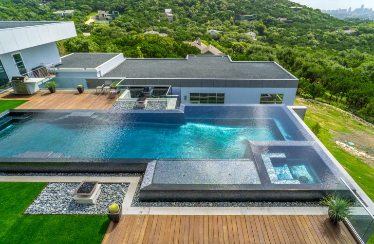 An infinity edge pool with imported tile and a waterfall. The decks are Ipe. Built by Greg Neff of CGN Premier Lonestar