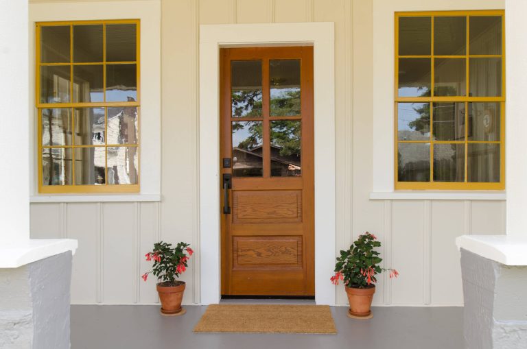 An old restored fir door, new wood windows and fresh paint give this cozy restored beach house a cheerful and welcoming entrance.