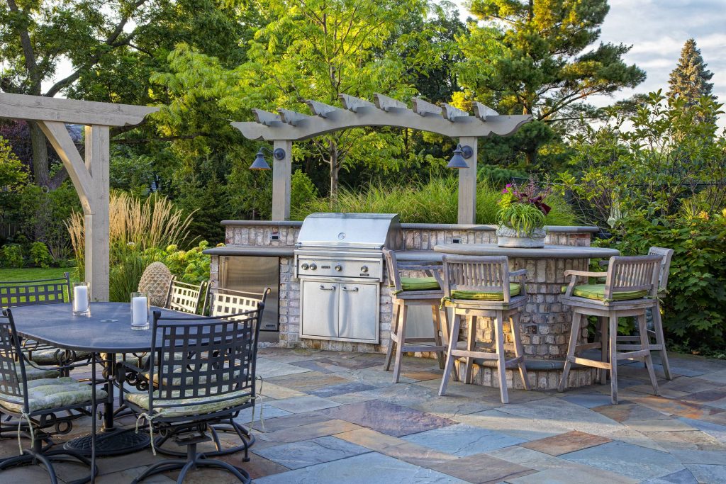 An outdoor kitchen adjacent to the family dining area offers well-lighted space for food preparation, with bar height seating, a stainless steel grill, refrigerator and a bluestone footrest.

by Hursthouse Landscape Architects and Contractors | Outdoor Kitchens | Backyard Design | Outdoor Living Spaces | Landscape Design