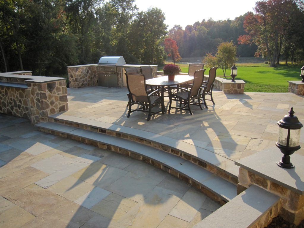 An outdoor living space with grill and ample counter space for gathering