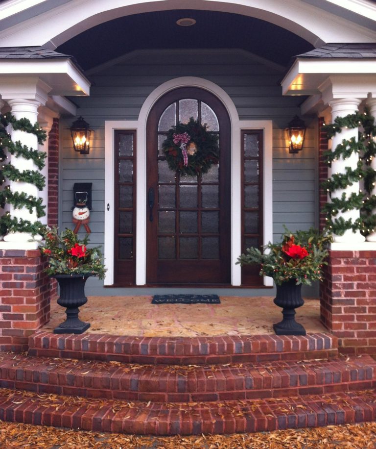 Ashley Street electric lanterns on a blue wooden and brick home that is decorated for the holidays.
