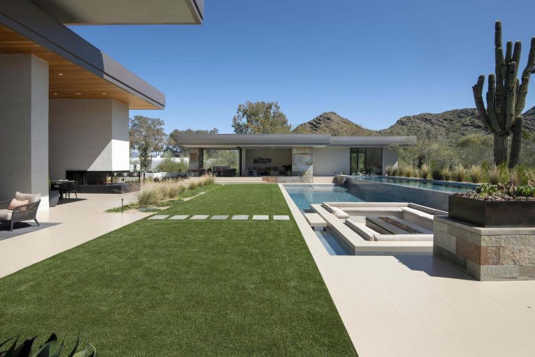 With adjacent neighbors within a fairly dense section of Paradise Valley, Arizona, C.P. Drewett sought to provide a tranquil retreat for a new-to-the-Valley surgeon and his family who were seeking the modernism they loved though had never lived in. With a goal of consuming all possible site lines and views while maintaining autonomy, a portion of the house — including the entry, office, and master bedroom wing — is subterranean. This subterranean nature of the home provides interior grandeur for guests but offers a welcoming and humble approach, fully satisfying the clients requests.

While the lot has an east-west orientation, the home was designed to capture mainly north and south light which is more desirable and soothing. The architecture’s interior loftiness is created with overlapping, undulating planes of plaster, glass, and steel. The woven nature of horizontal planes throughout the living spaces provides an uplifting sense, inviting a symphony of light to enter the space. The more voluminous public spaces are comprised of stone-clad massing elements which convert into a desert pavilion embracing the outdoor spaces. Every room opens to exterior spaces providing a dramatic embrace of home to natural environment.

Grand Award winner for Best Interior Design of a Custom Home
The material palette began with a rich, tonal, large-format Quartzite stone cladding. The stone’s tones gaveforth the rest of the material palette including a champagne-colored metal fascia, a tonal stucco system, and ceilings clad with hemlock, a tight-grained but softer wood that was tonally perfect with the rest of the materials. The interior case goods and wood-wrapped openings further contribute to the tonal harmony of architecture and materials.

Grand Award Winner for Best Indoor Outdoor Lifestyle for a Home This award-winning project was recognized at the 2020 Gold Nugget Awards with two Grand Awards, one for Best Indoor/Outdoor Lifestyle for a Home, and another for Best Interior Design of a One of a Kind or Custom Home.

At the 2020 Design Excellence Awards and Gala presented by ASID AZ North, Ownby Design received five awards for Tonal Harmony. The project was recognized for 1st place – Bathroom; 3rd place – Furniture; 1st place – Kitchen; 1st place – Outdoor Living; and 2nd place – Residence over 6,000 square ft. Congratulations to Claire Ownby, Kalysha Manzo, and the entire Ownby Design team.

Tonal Harmony was also featured on the cover of the July/August 2020 issue of Luxe Interiors + Design and received a 14-page editorial feature entitled “A Place in the Sun” within the magazine.
by Drewett Works | Pool design | Pool Contracting | Swimming Pool Ideas | Swimming Pool Design Ideas
