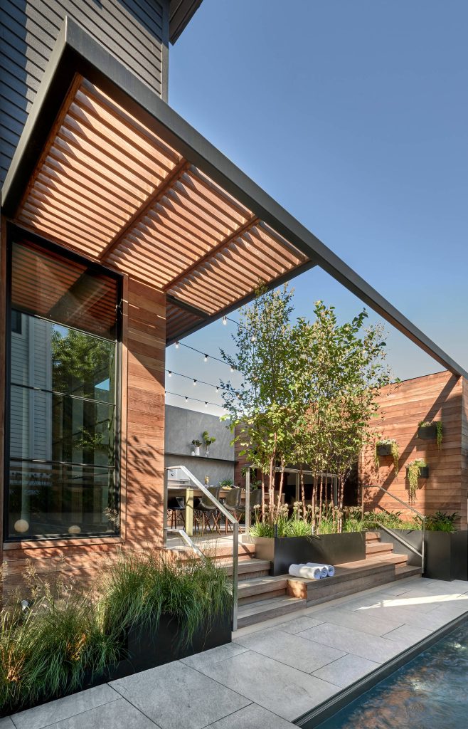 Back deck opens out to the side; stone pavers frame a sunken rectangular pool. Tony Soluri Photography