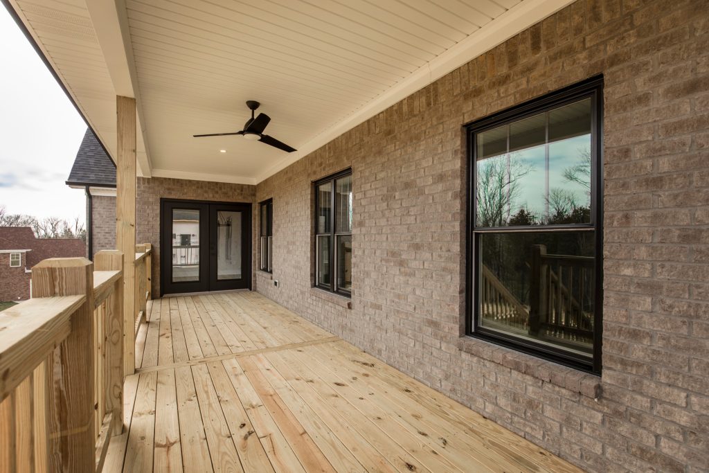 Back porch of transitional home. Double doors and an overhead fan.