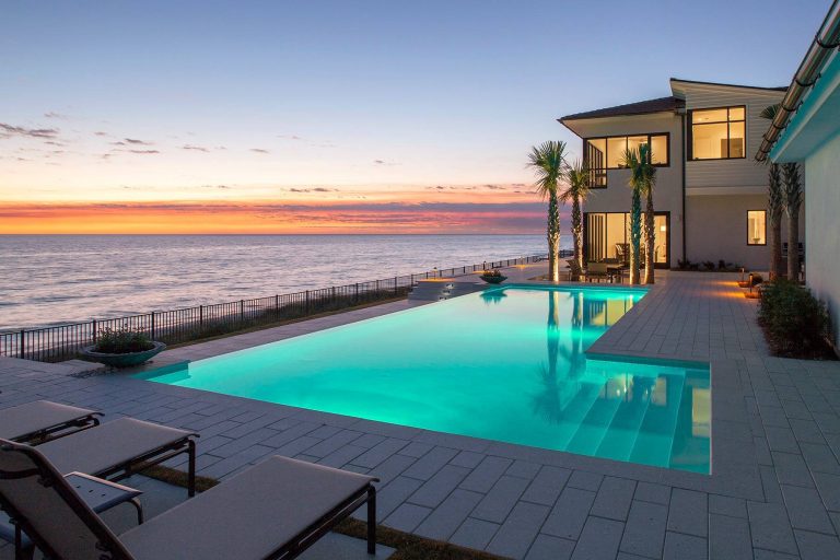 Beach style backyard l-shaped infinity pool photo in Miami