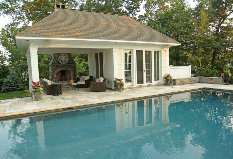 Beautiful pavilion style pool house with kitchen, eating area, bathroom along with exterior fireplace and seating area.