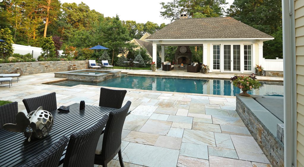 Beautiful pavilion style pool house with kitchen, eating area, bathroom and exterior fireplace and sitting area.