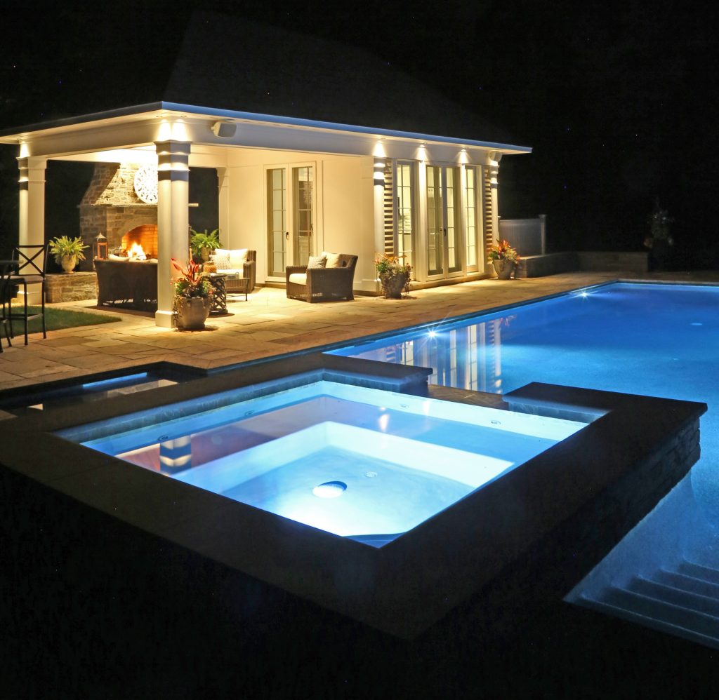 Beautiful pavilion style pool house with kitchen, eating area, bathroom and exterior fireplace and sitting area.