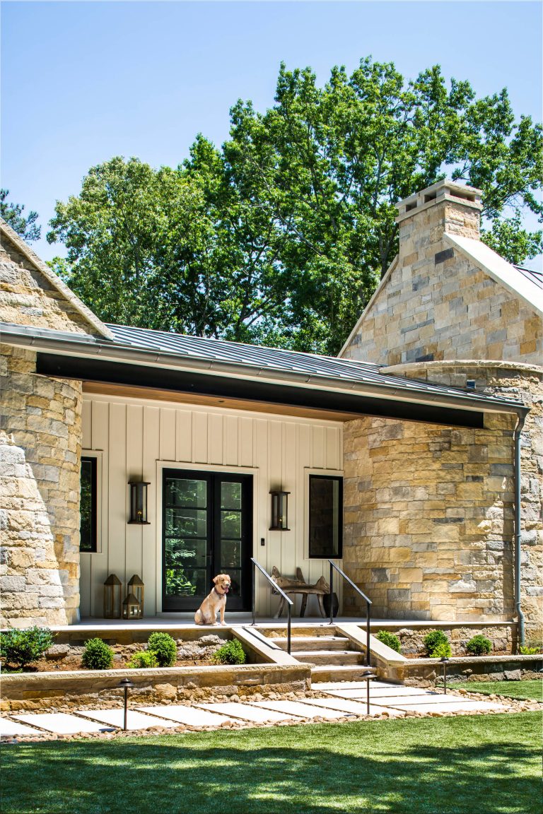 Best golden retriever ever showcasing the front facade of our Modern Farmhouse, featuring a metal roof, limestone surround and custom gas lanterns. Photo by Jeff Herr Photography. by Jane Group Inc. | Outdoor Photos | Porch | Landscaping | Landscape Design | Outdoor Living Space | Porch Design Ideas | Outdoor Living Space Ideas | Backyard Design