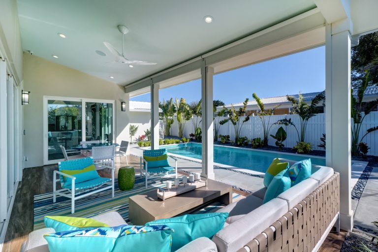 Black river rock and concrete slabs around modern pool with limestone coping