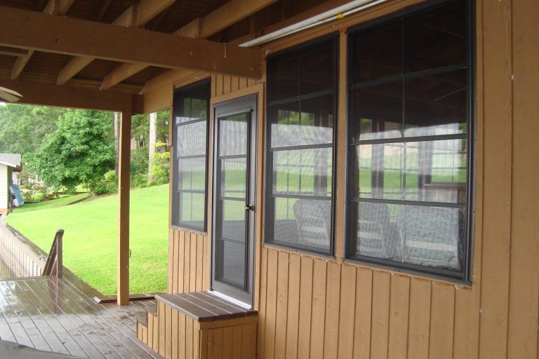 Boathouse porch enclosure with WeatherMaster adjustable windows and chairs inside that overlook boat dock.