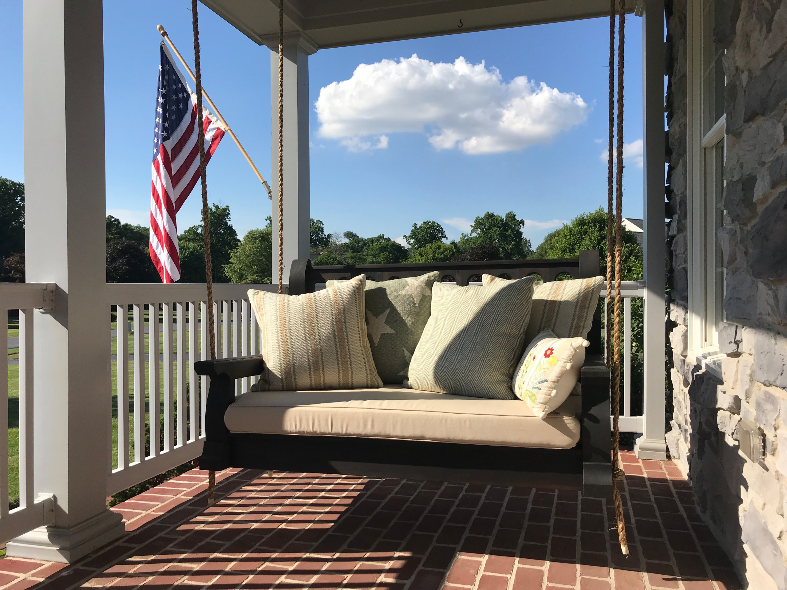 Classic style Nostalgic Porch Swing in the Ebony stained finish and natural manila ropes.
This is an example of a mid-sized traditional brick porch design in Other with a roof extension.