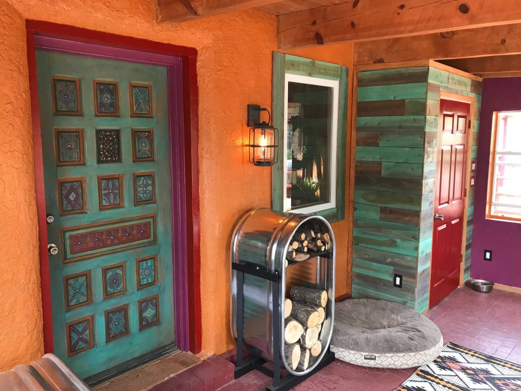 Colorful New Mexico Southwest Sun Porch / Entry by Fusion Art Interiors. Artisan painted door and tuquoise stained cedar wood plank accents. Custom cattle stock tank fire wood holder. photo by C Beikmann by Fusion Art Interiors | Outdoor Photos | Porch | Landscaping | Landscape Design | Outdoor Living Space | Porch Design Ideas | Outdoor Living Space Ideas | Backyard Design