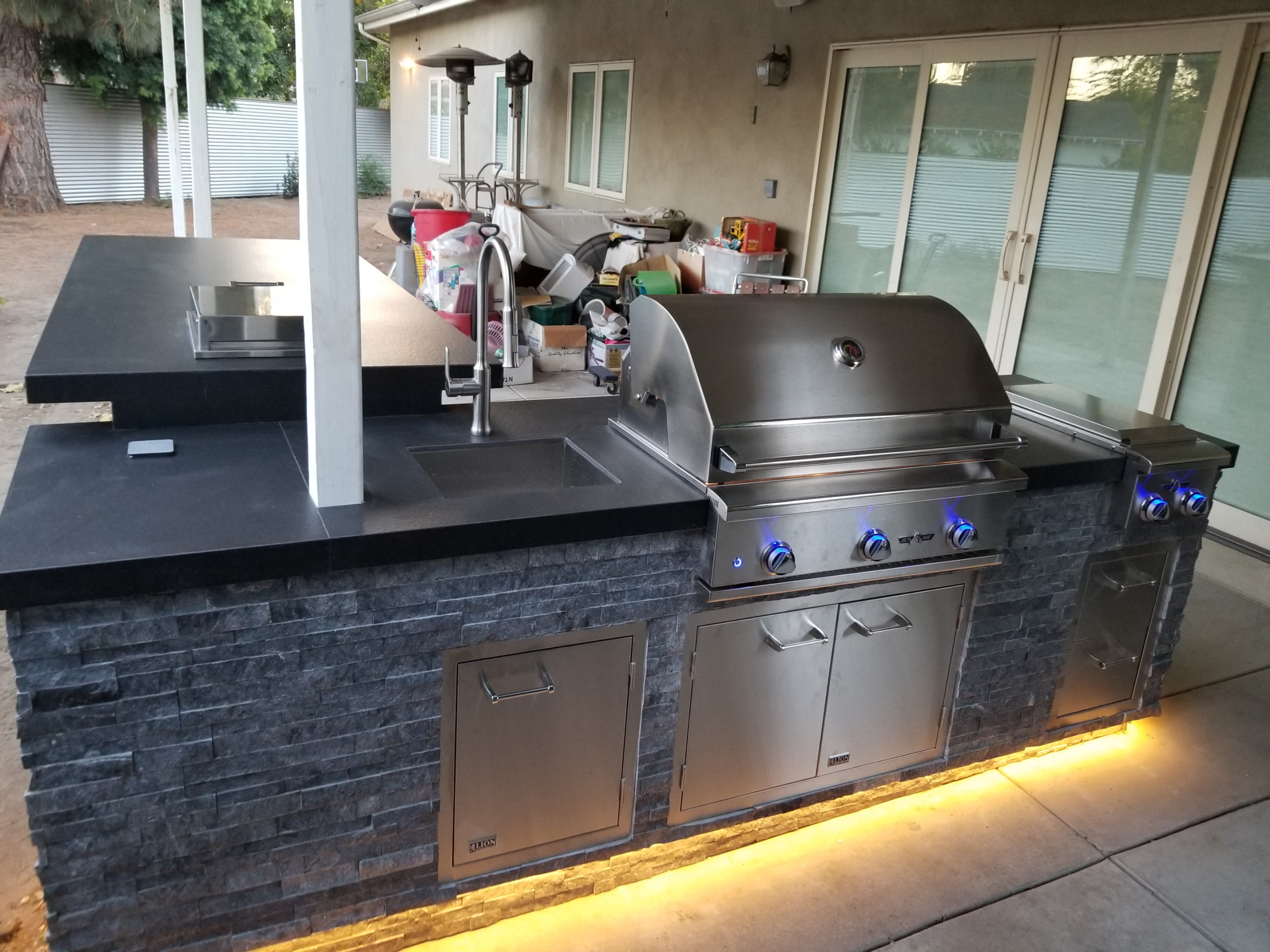 Contemporary L-shape Island with Delta Heat grill and raised bar with a pop-up outlet
Trendy backyard patio kitchen photo in Los Angeles
