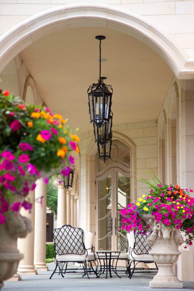 Covered Loggia back patio with beautiful flower pots, gas lanterns, custom exterior coos, slate tile floors and Indiana limestone exterior.