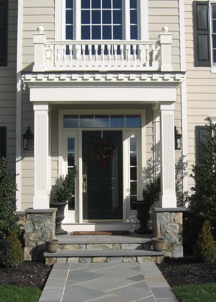 Covered front porch located in Laytonsville MD includes fluted columns, stone pedestals, flagstone walkway and widow walk.