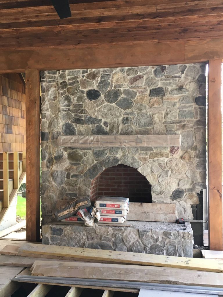 Covered porch with stone fireplace and reclaimed wood ceiling and posts. Outdoor kitchen awaiting installation.