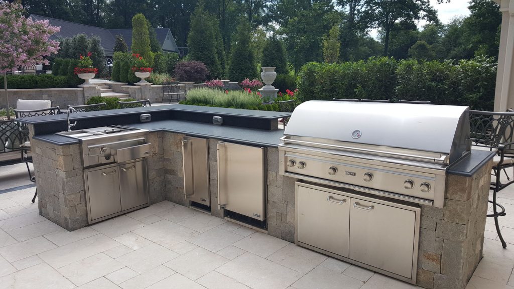 Custom Outdoor Kitchen with High end Lynx Grill, Granite Countertop, Outdoor Refrigerator, Warming Drawer Outoor sink. The floor is Travertine installed to a French pattern