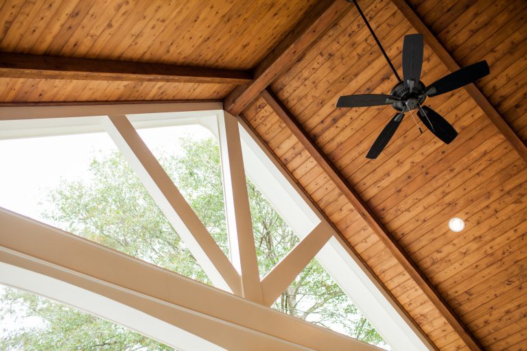 Custom cedar tongue and groove ceiling with exposed beams, can lights, and ceiling fans.