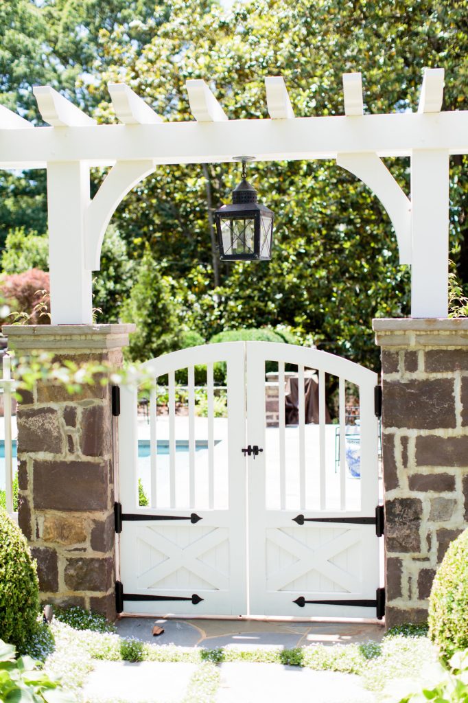 Custom designed entry gates mounted on stone columns and covered by a beautifully lit pergola, open into the new, repositioned pool area.