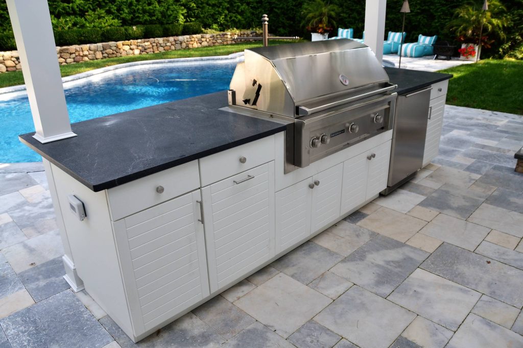 Custom outdoor kitchen design on outdoor poolside patio