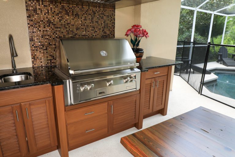 Custom outdoor kitchen featuring 100% weatherproof cabinets, gas grill and vent hood.